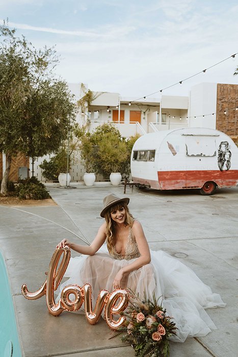 A bride posing with flowers and balloons 