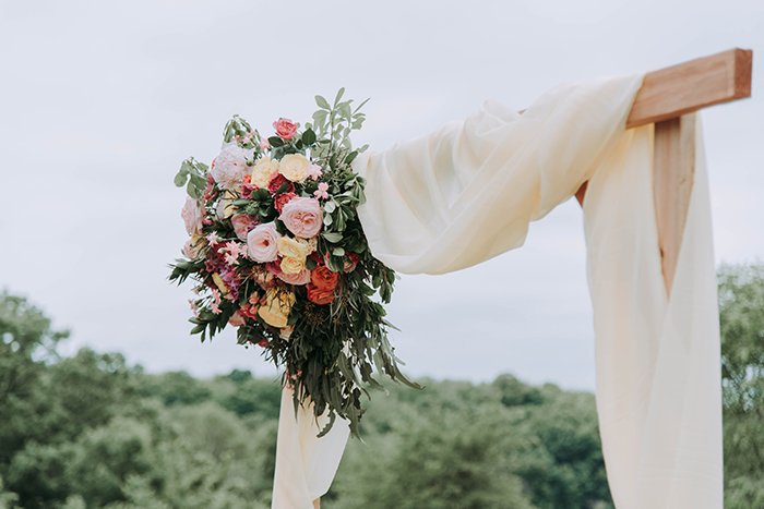 A wooden arch decorated with fabric and flowers 